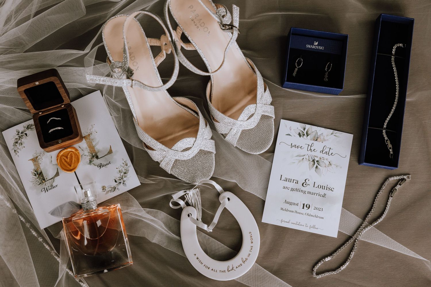Wedding accessories including shoes, jewelry boxes, and invitation cards arranged on fabric.