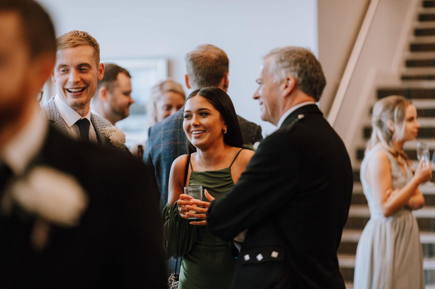Wedding guests enjoying conversation and drinks at an elegant indoor reception.