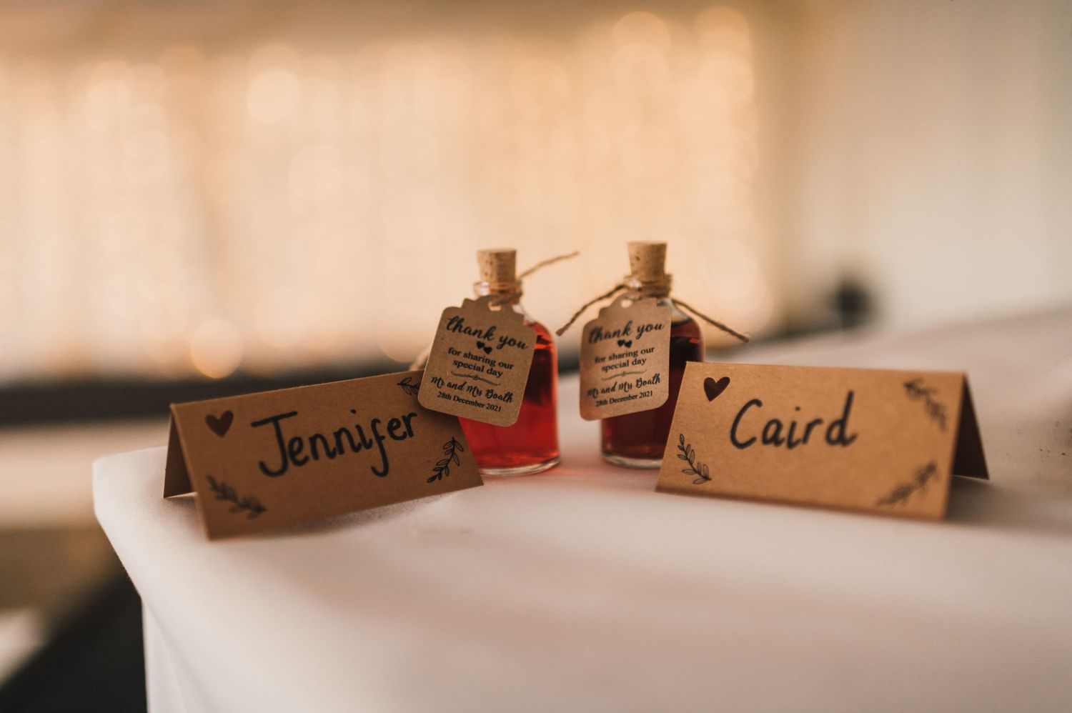 Rustic wedding place cards with name tags and small decorative bottles on a white surface.