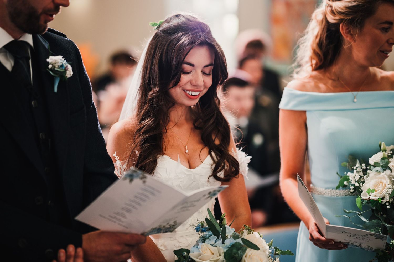 Close up shot of wedding ceremony participants holding programs and bouquets.