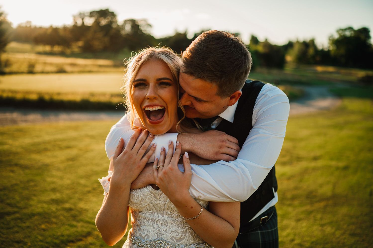 A joyful moment captured between a couple in wedding attire on a golf course at sunset.