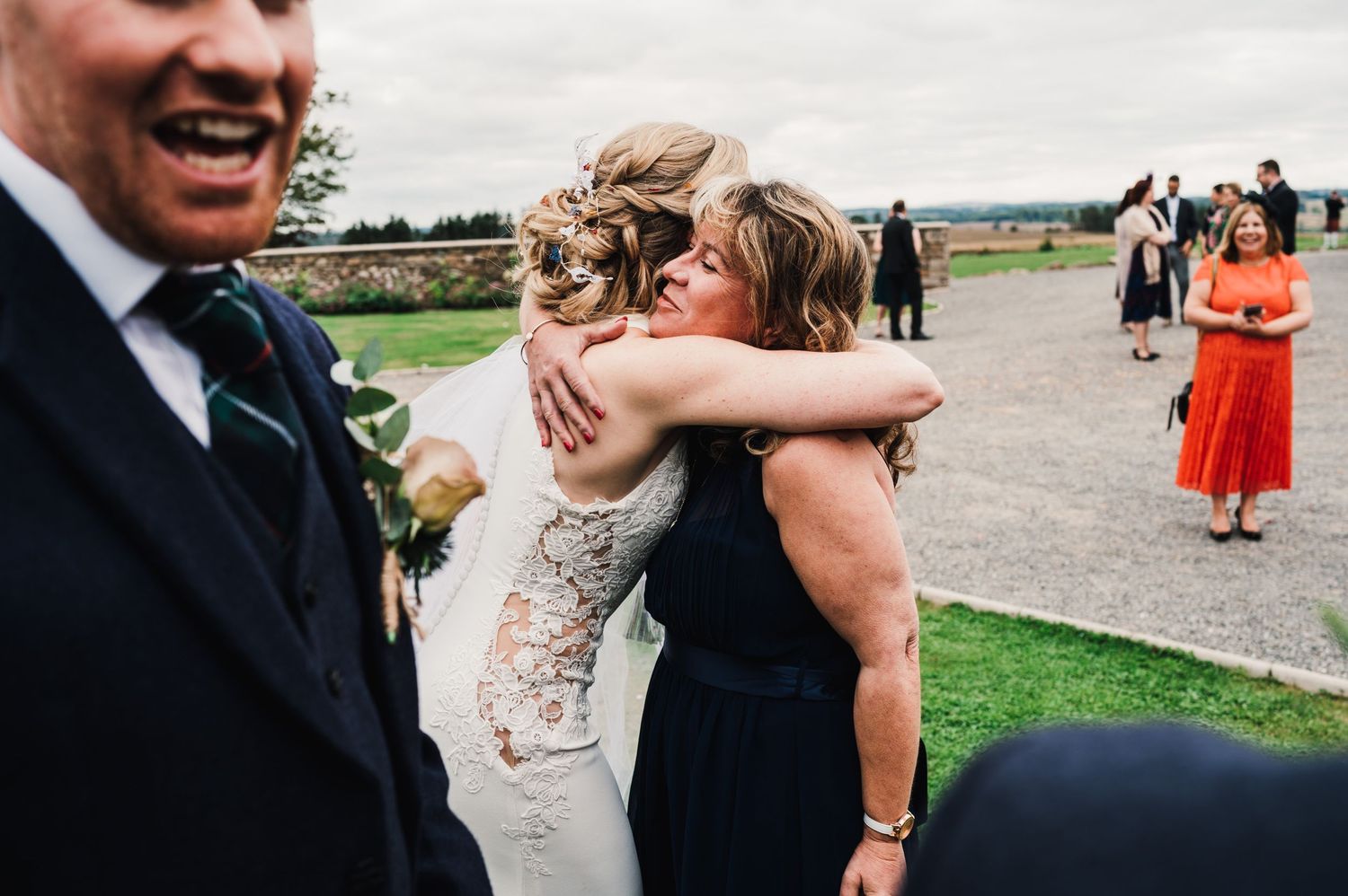 Candid moment of wedding guests hugging during outdoor celebration.
