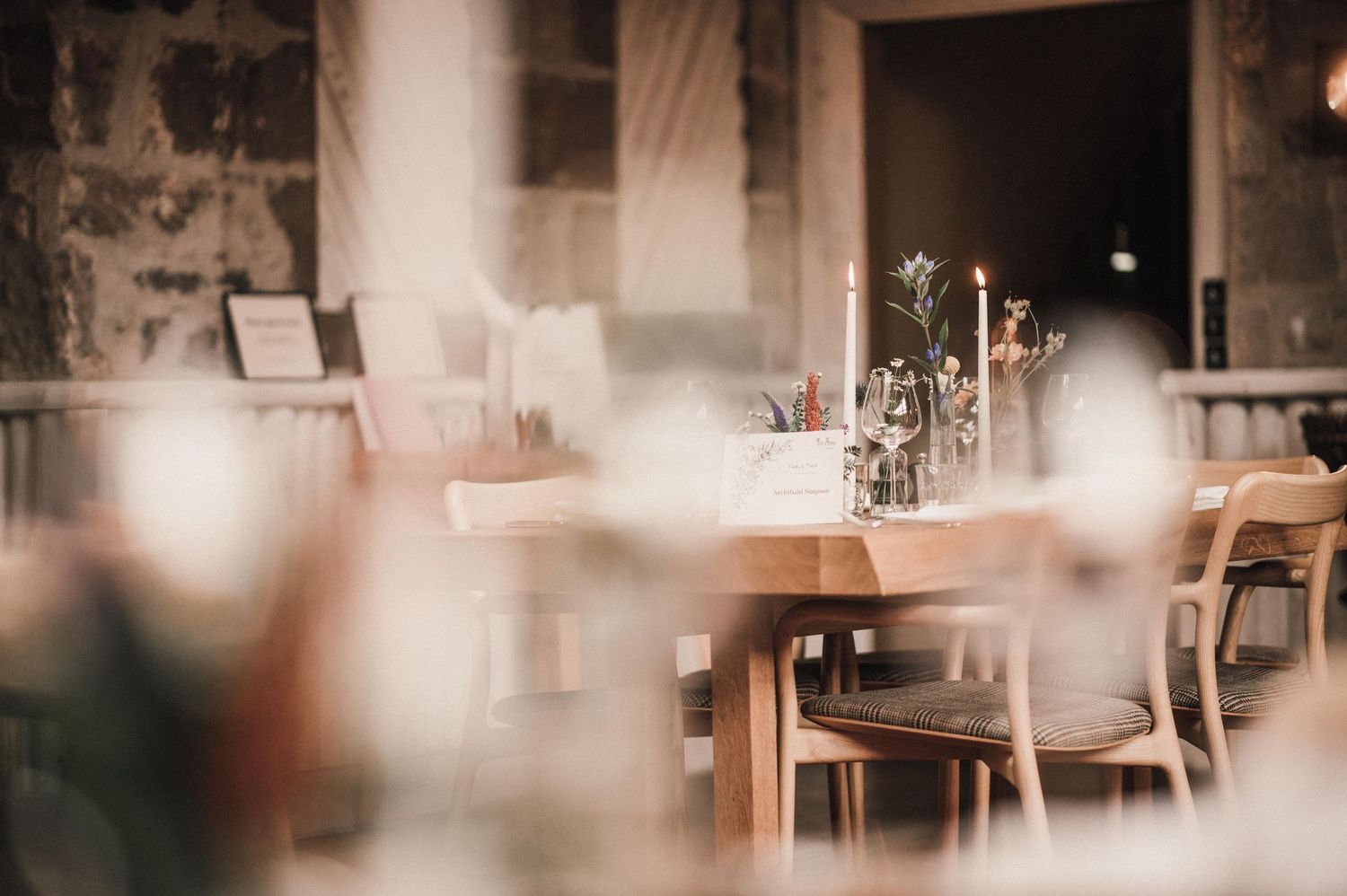 Soft focus view of restaurant interior with wooden tables and chairs in warm lighting.