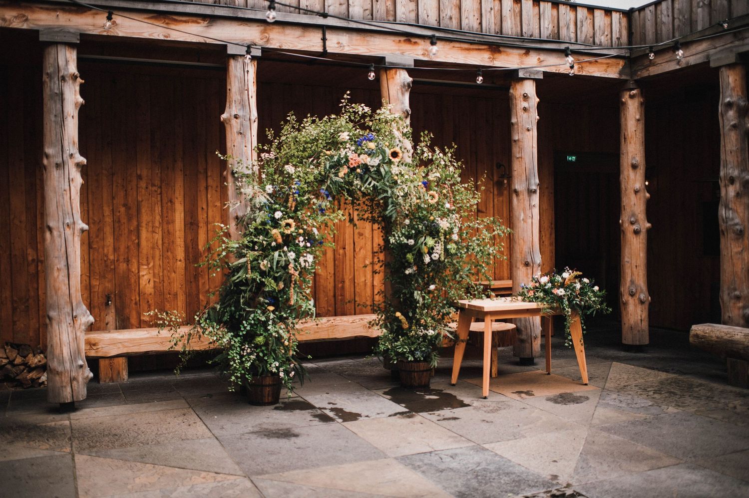 Rustic wooden arch decorated with climbing vines and flowers for a wedding ceremony.