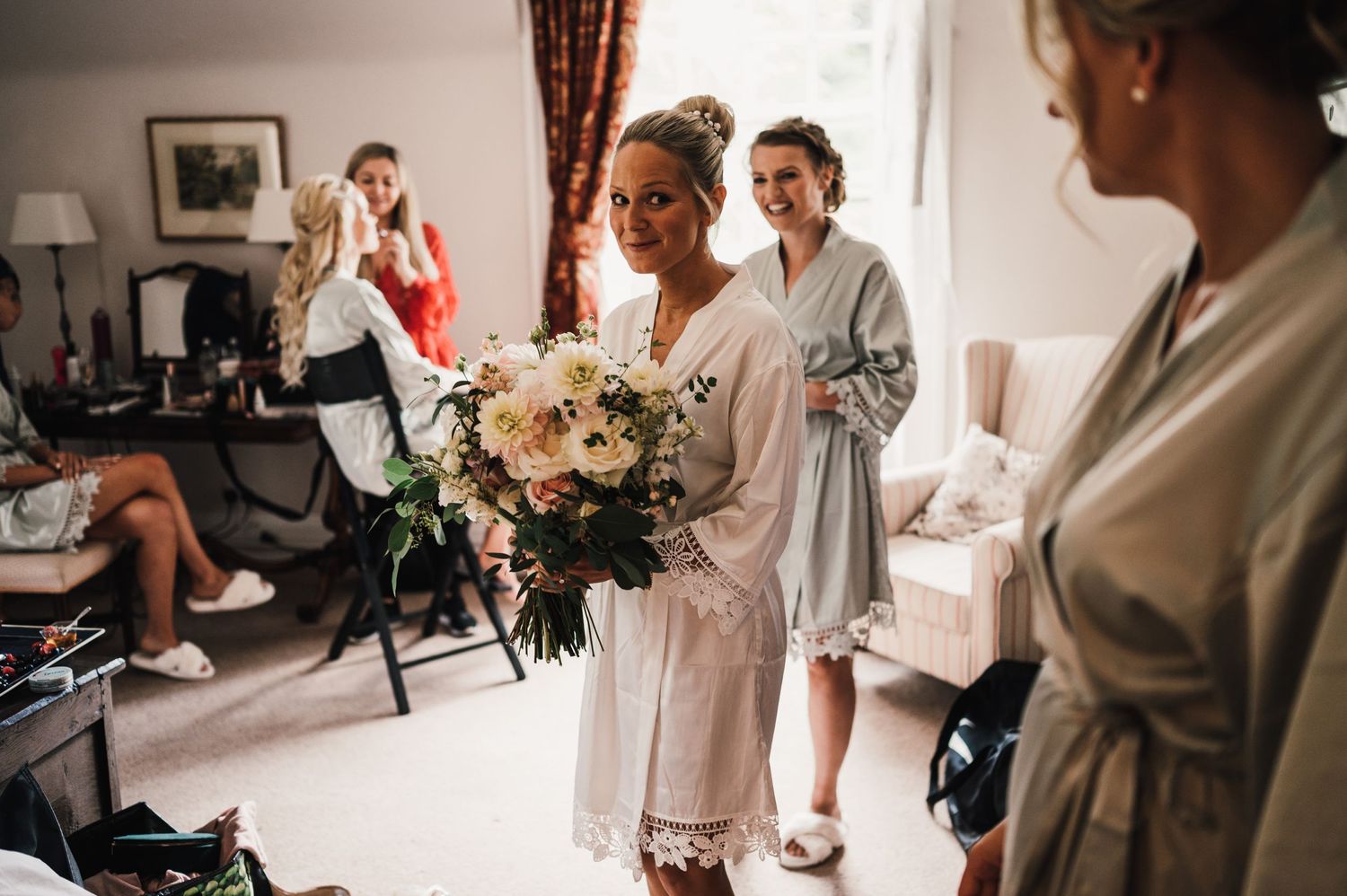 Wedding party members in matching robes prepare for the ceremony while holding a beautiful white floral bouquet.