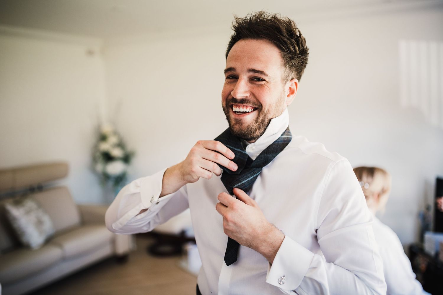 Someone adjusting a formal black tie while getting dressed.
