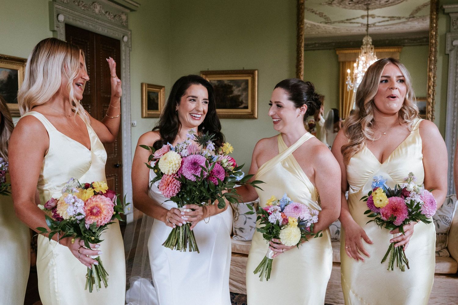 Bridal party holding colorful bouquets while wearing matching white dresses.