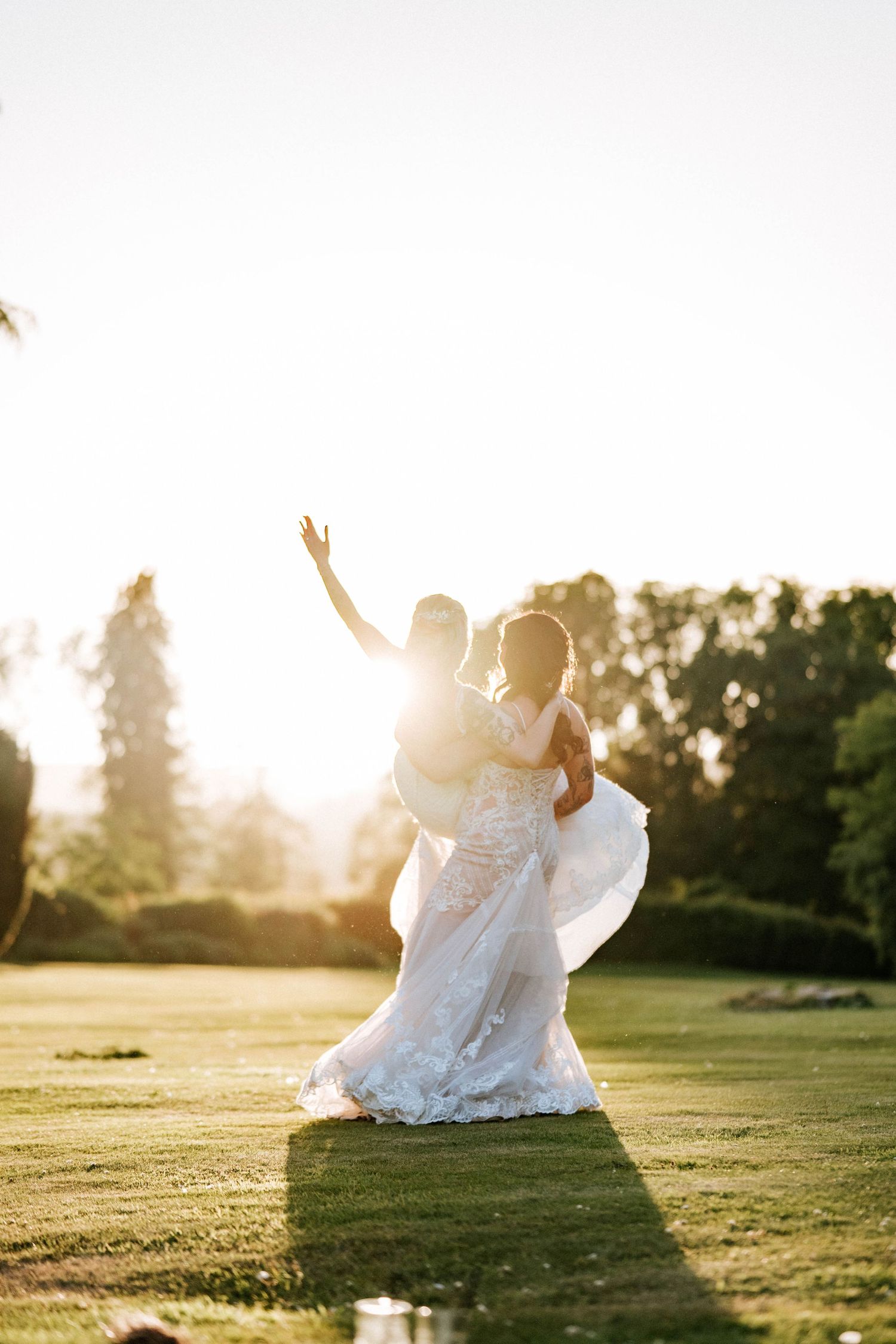 Aberdeen Wedding Photography. Wedding couple in white dresses dance and twirl on grass during golden hour.