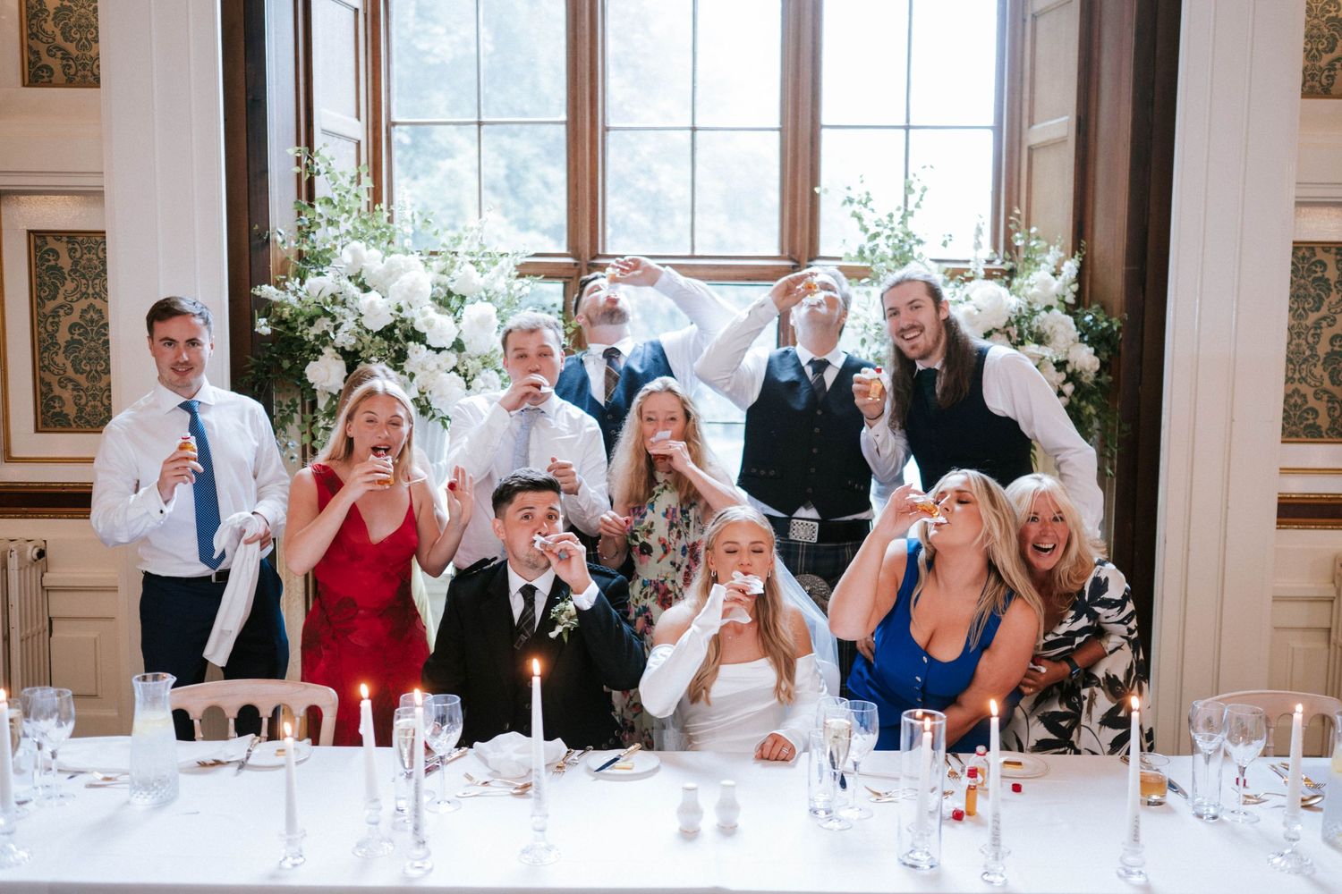 Wedding reception guests react with excitement during speeches at elegant indoor venue.