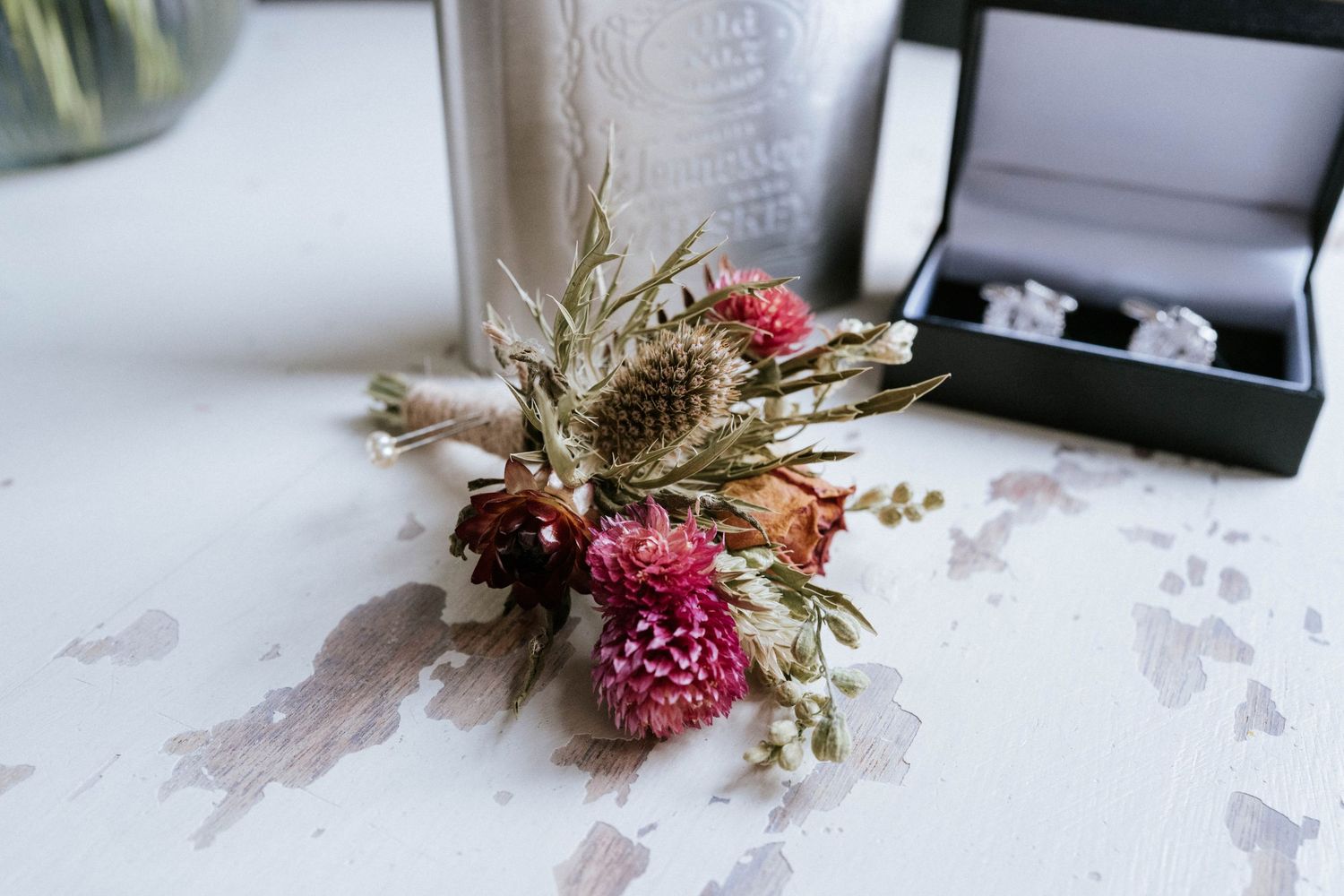Wedding accessories and dried floral arrangements displayed on a white textured surface with vintage elements.