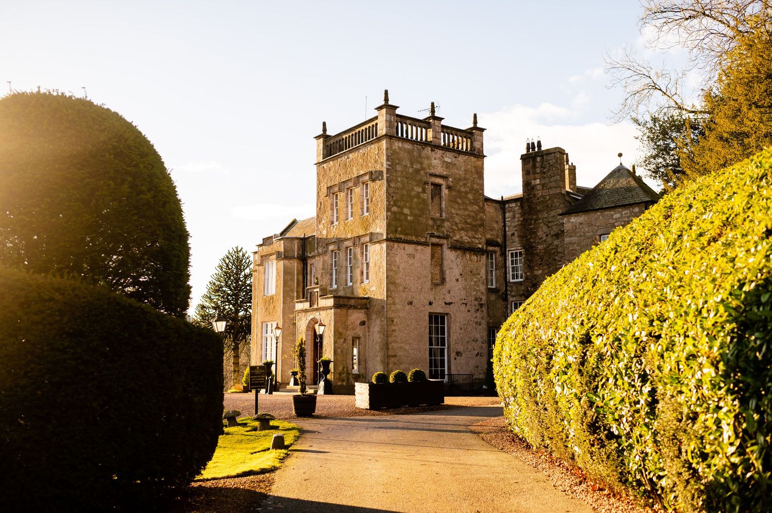 Historic stone castle mansion with tower photographed in golden sunlight.