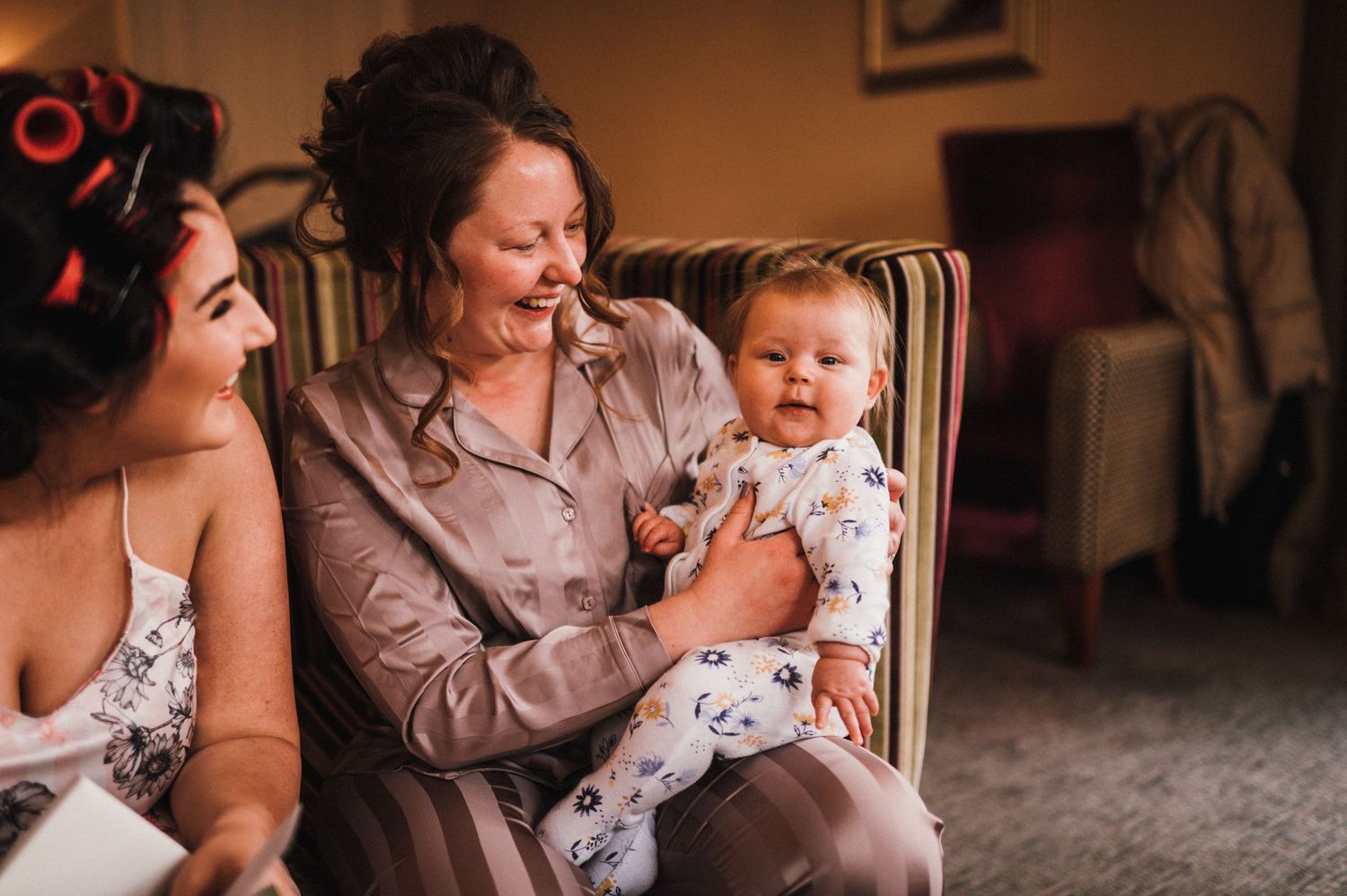 Candid moment of family sharing laughs with baby on striped couch.