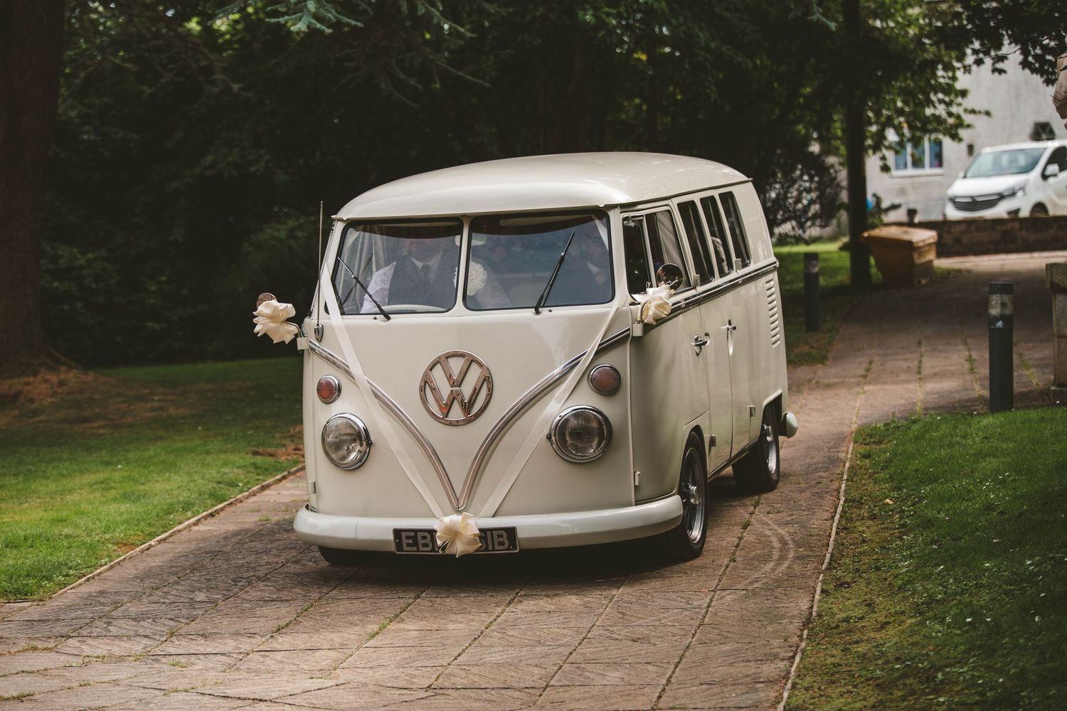 Classic white Volkswagen van parked on a driveway, serving as wedding transportation.