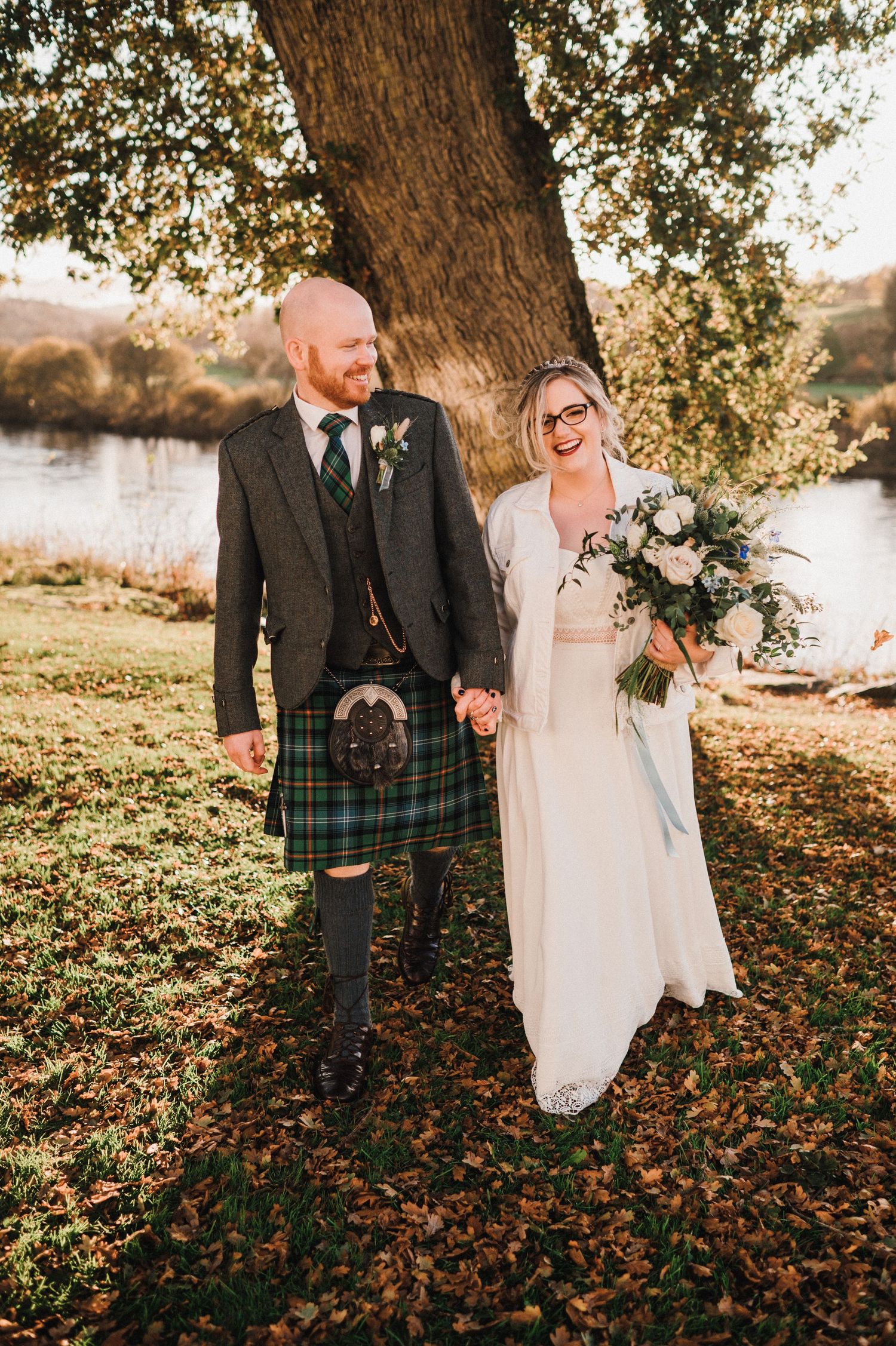 Beautiful outdoor wedding photos by a lake with traditional Scottish attire.