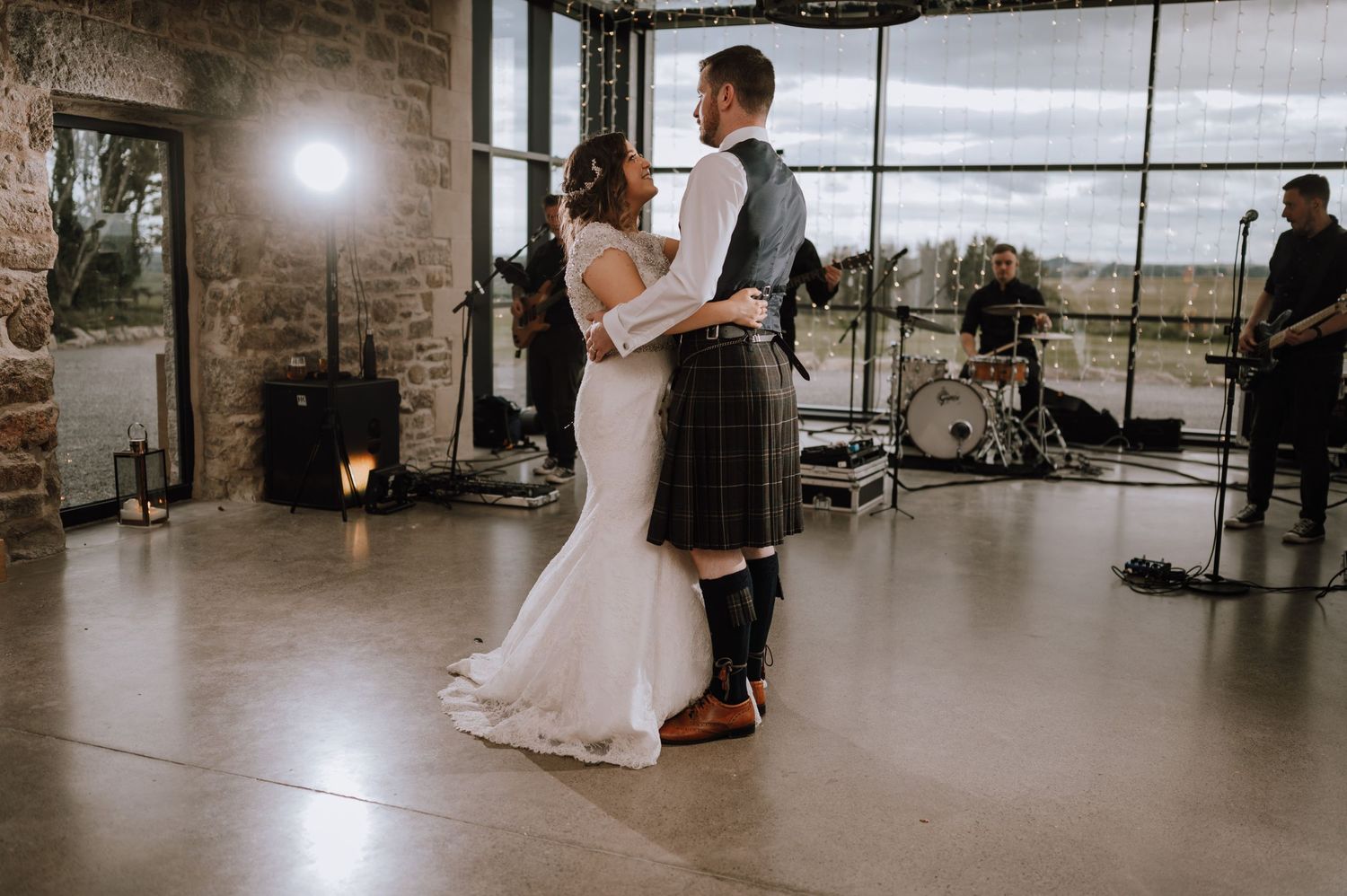 Wedding celebration in a modern venue with floor-to-ceiling windows overlooking a scenic landscape.