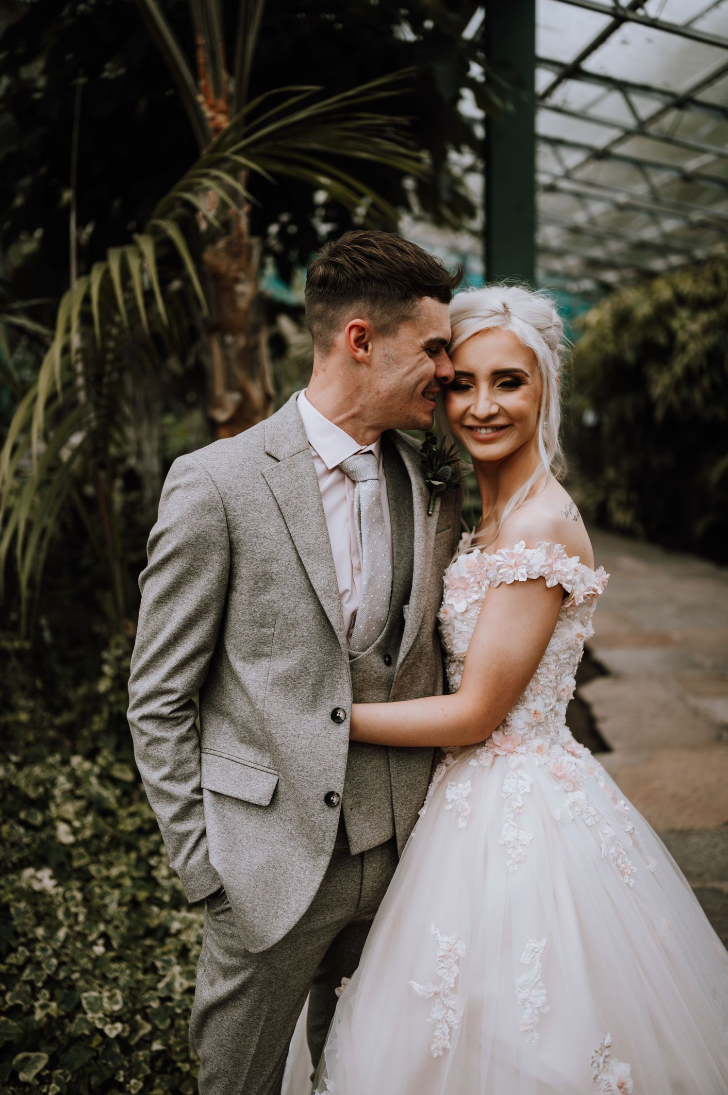Intimate wedding portrait in a botanical greenhouse with tropical plants.