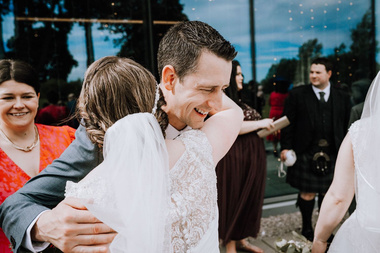Joyful embraces and laughter shared during outdoor wedding reception.