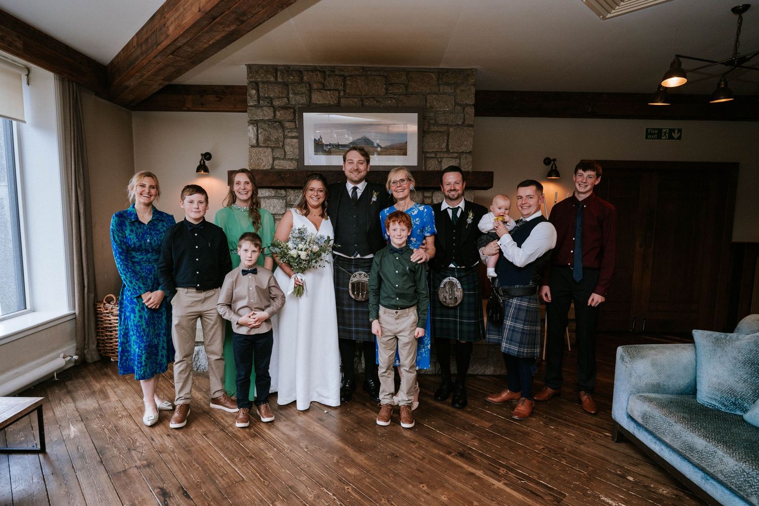 Panoramic view of wedding guests mingling in a rustic indoor reception venue with exposed beams.
