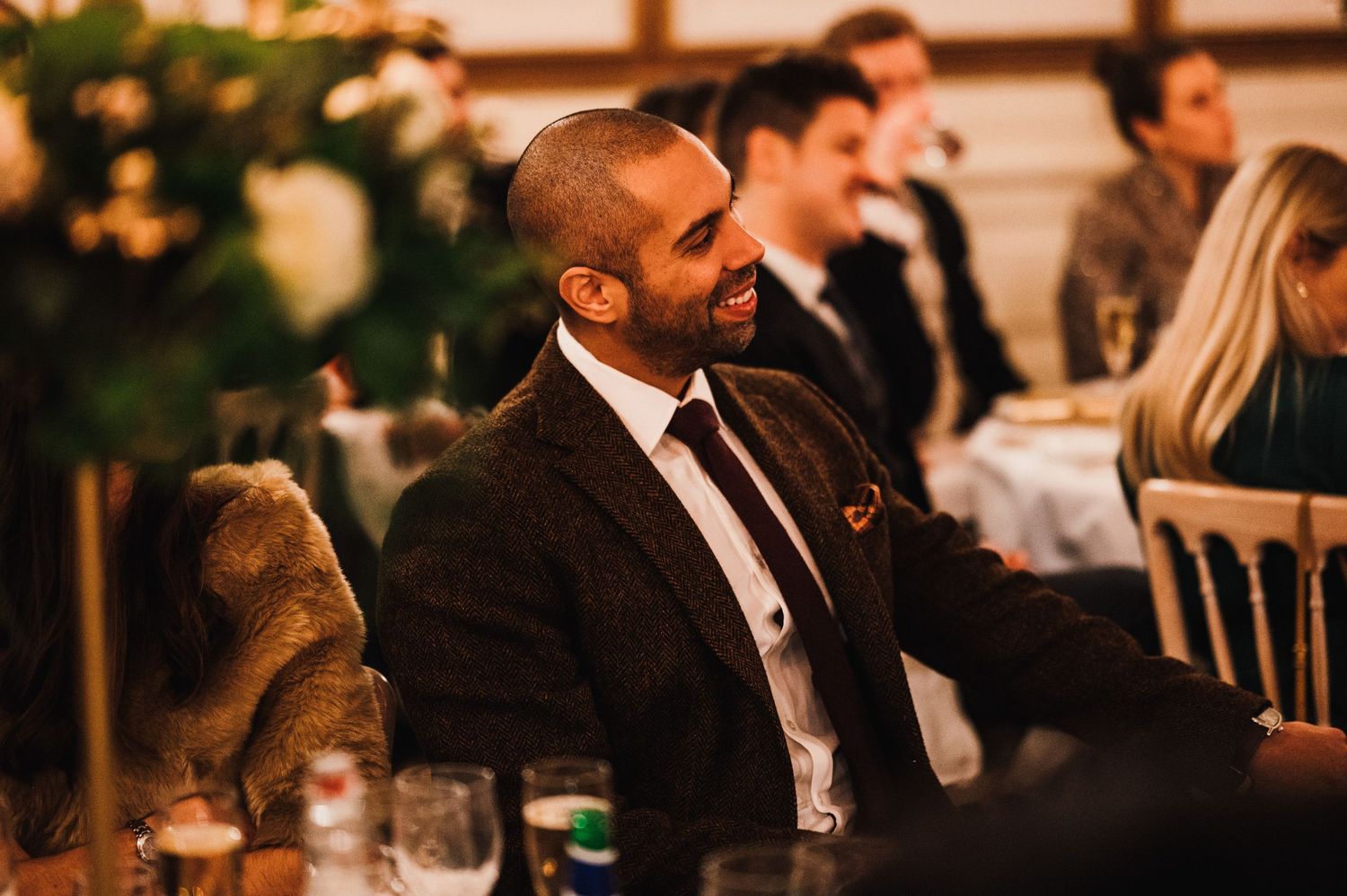 Guest in dark suit smiles during elegant evening reception.