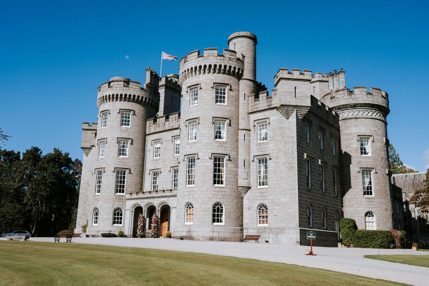 Exterior view of a majestic grey stone castle with turrets and Gothic architectural details.