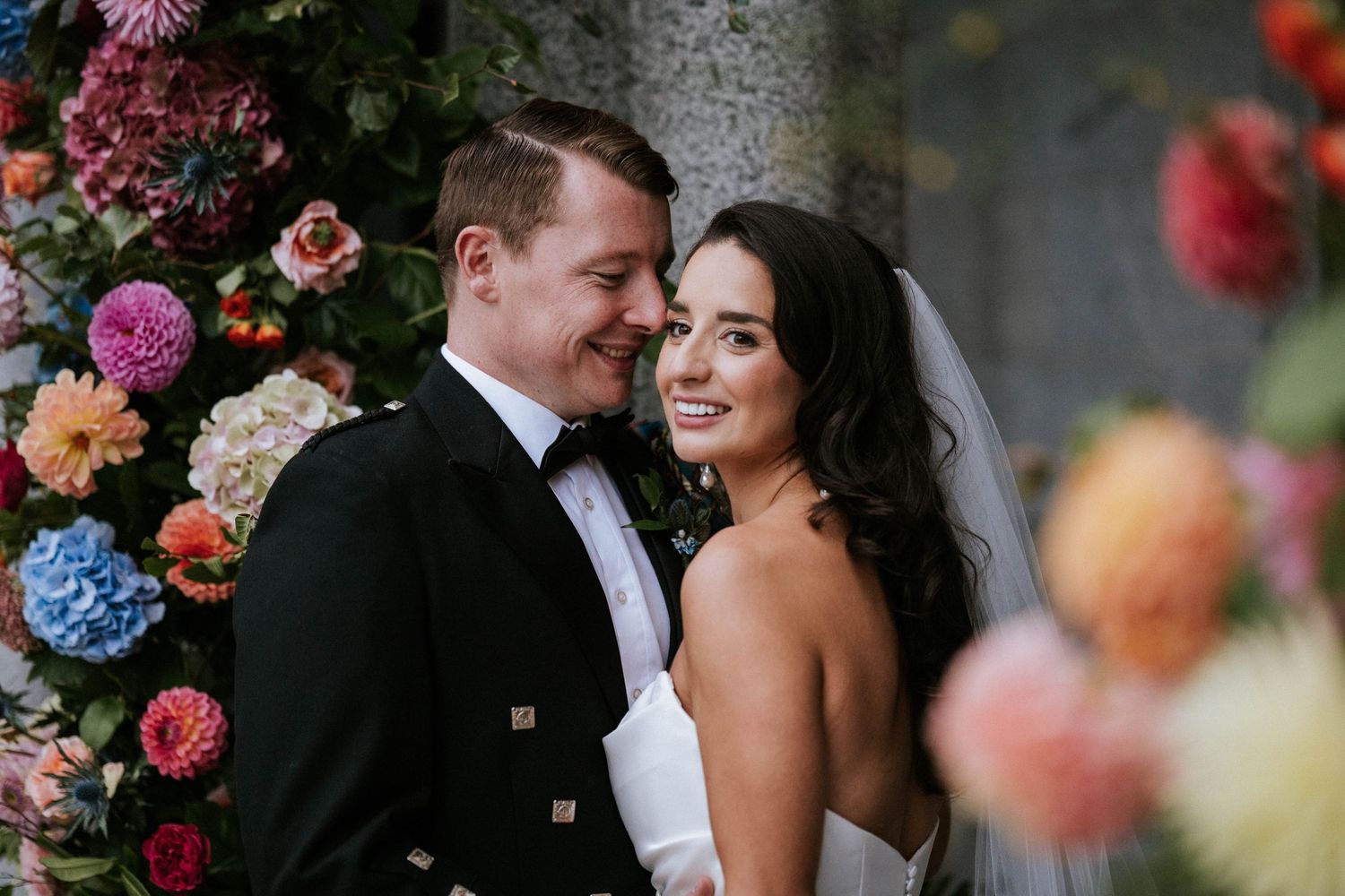 A romantic moment captured between a couple surrounded by colorful floral arrangements.