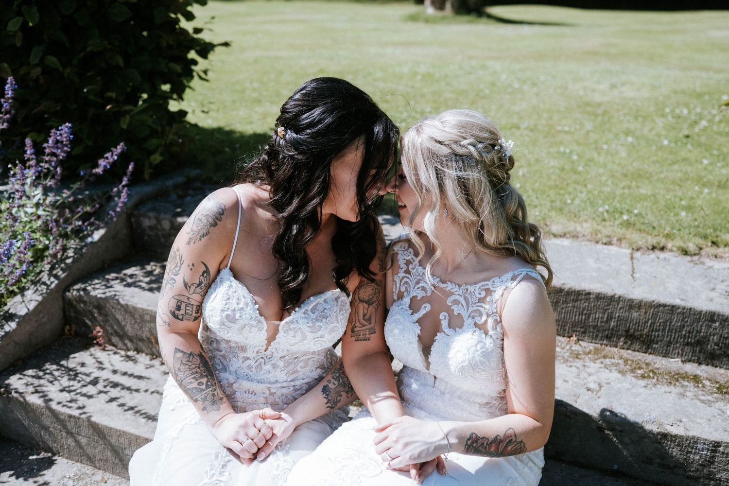 Couple in matching white wedding dresses share tender moments in an outdoor setting.