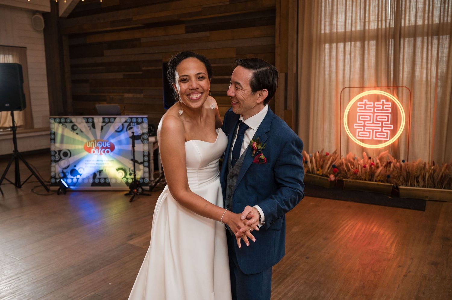 Wedding celebration in rustic indoor venue with neon lighting.