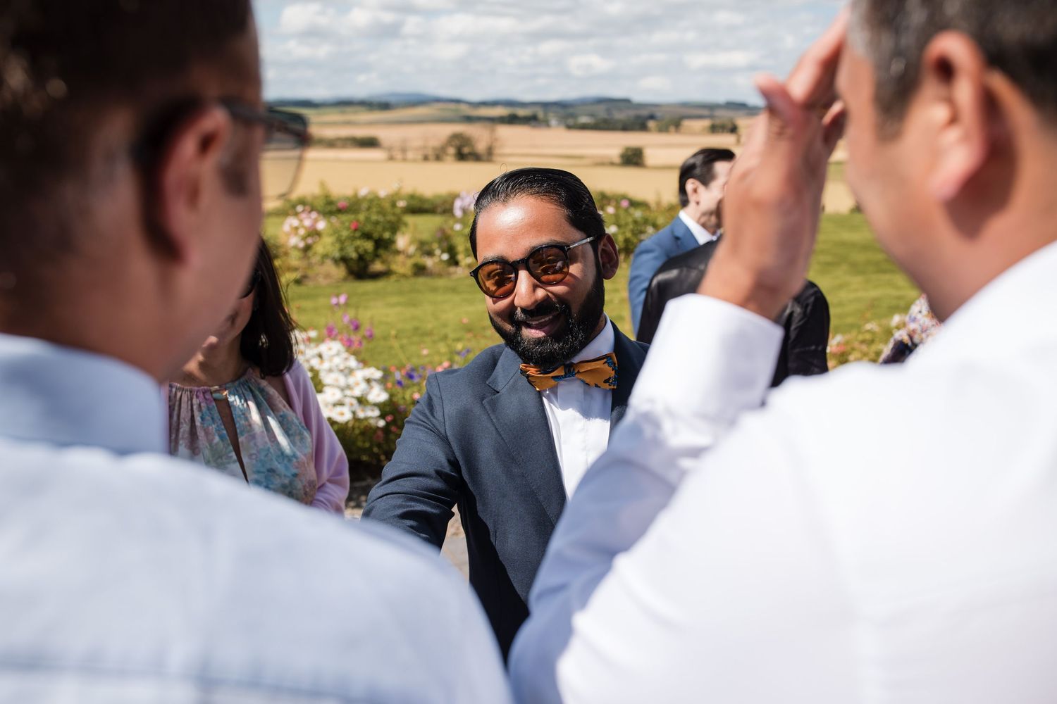 Wedding guests gather outdoors under cloudy skies for a celebration.
