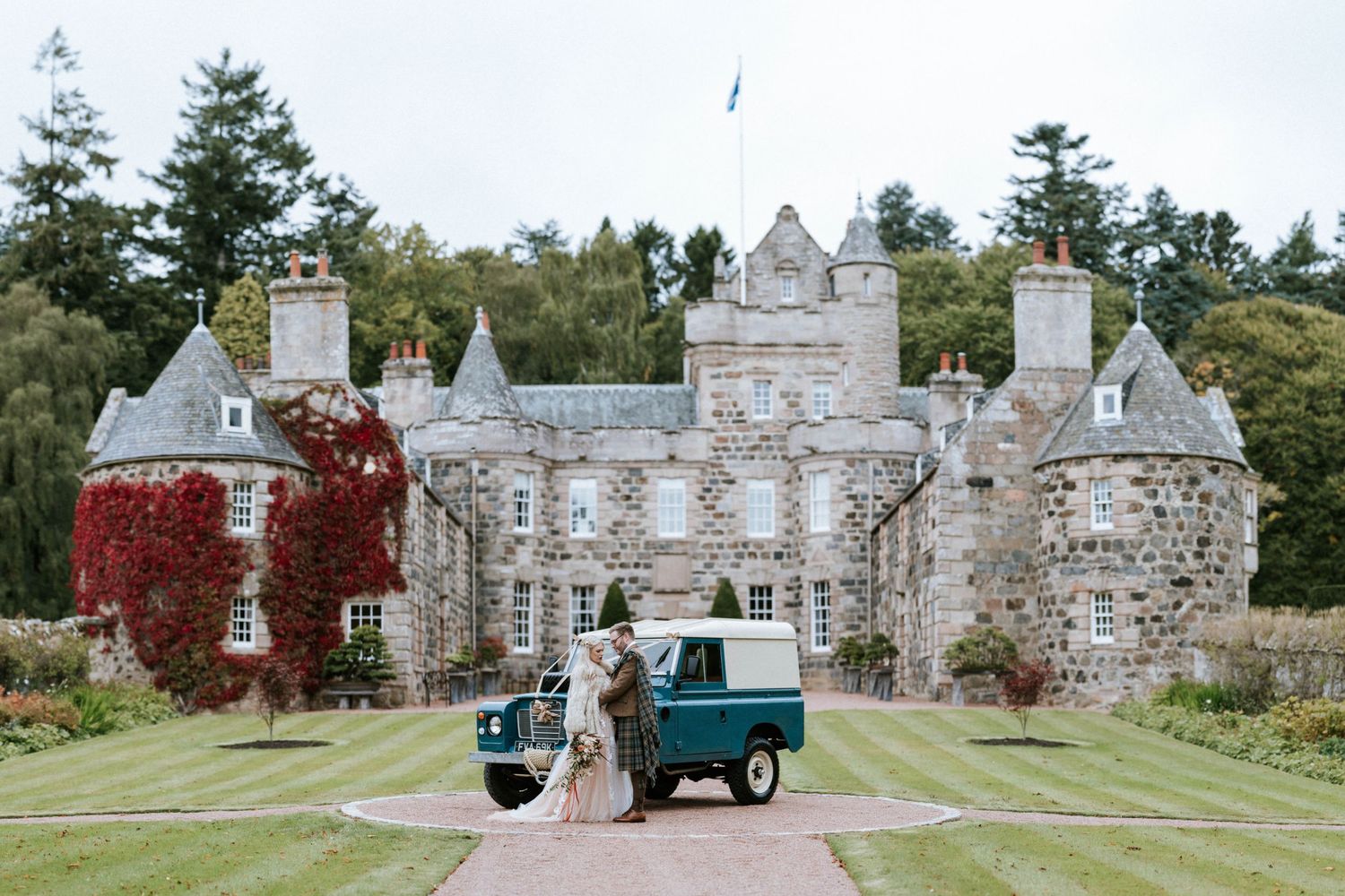 Historic stone castle estate with ivy-covered walls and manicured lawns serves as a grand wedding venue.