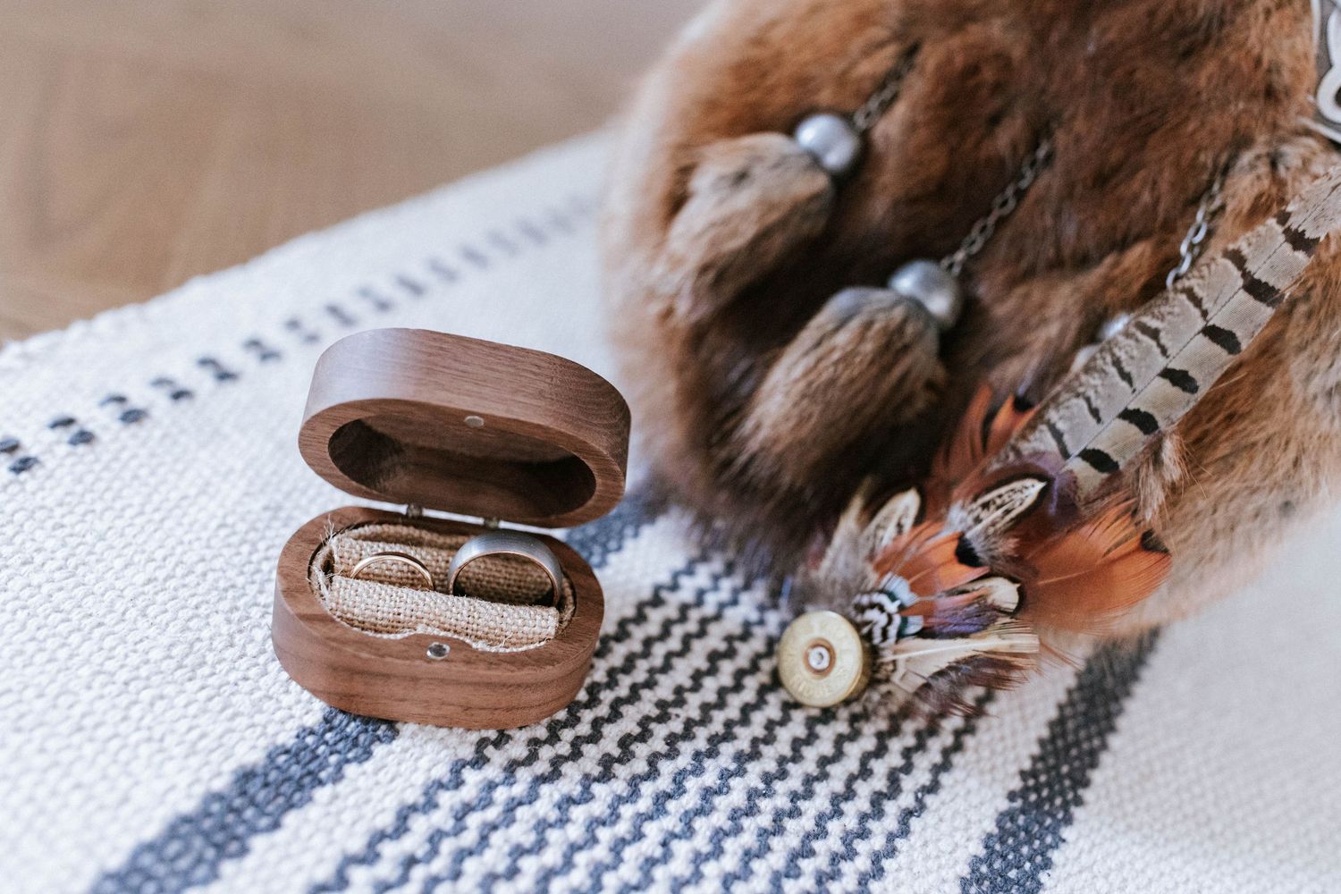 Close-up details of vintage wedding accessories including a leather belt and feather on a textured surface.