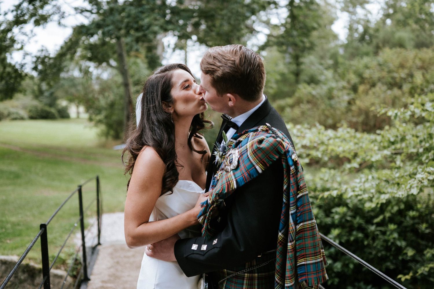 A tender moment between newlyweds with the groom in traditional Scottish kilt attire.