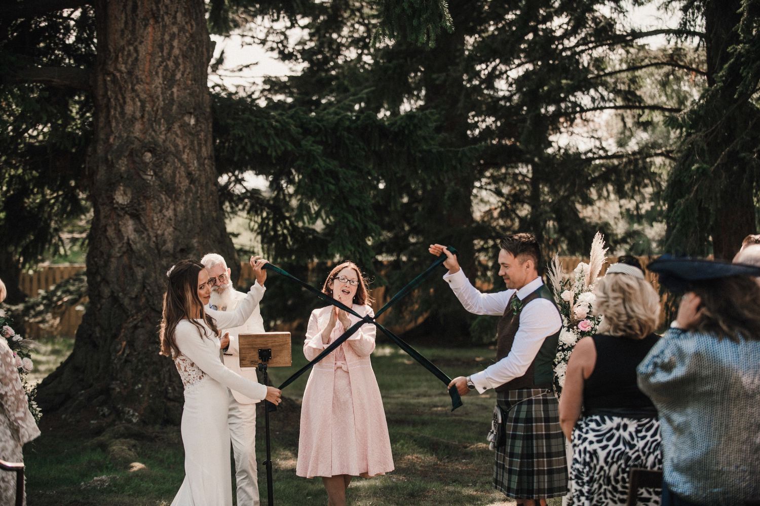 Wedding guests celebrate and dance together during an outdoor forest reception.