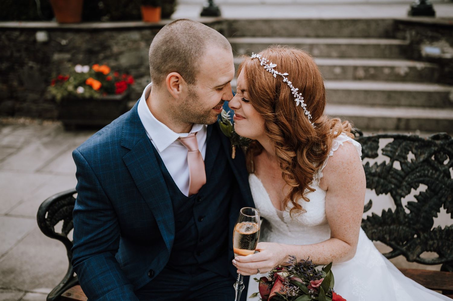 Romantic moment shared on stone steps adorned with floral decorations during wedding celebration.