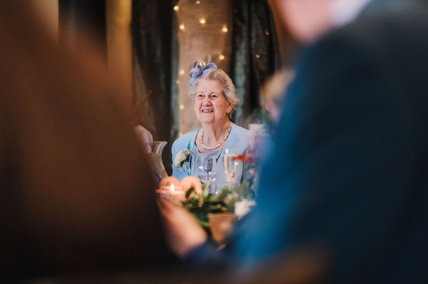 A guest enjoying a moment during a wedding celebration with twinkling lights in the background.