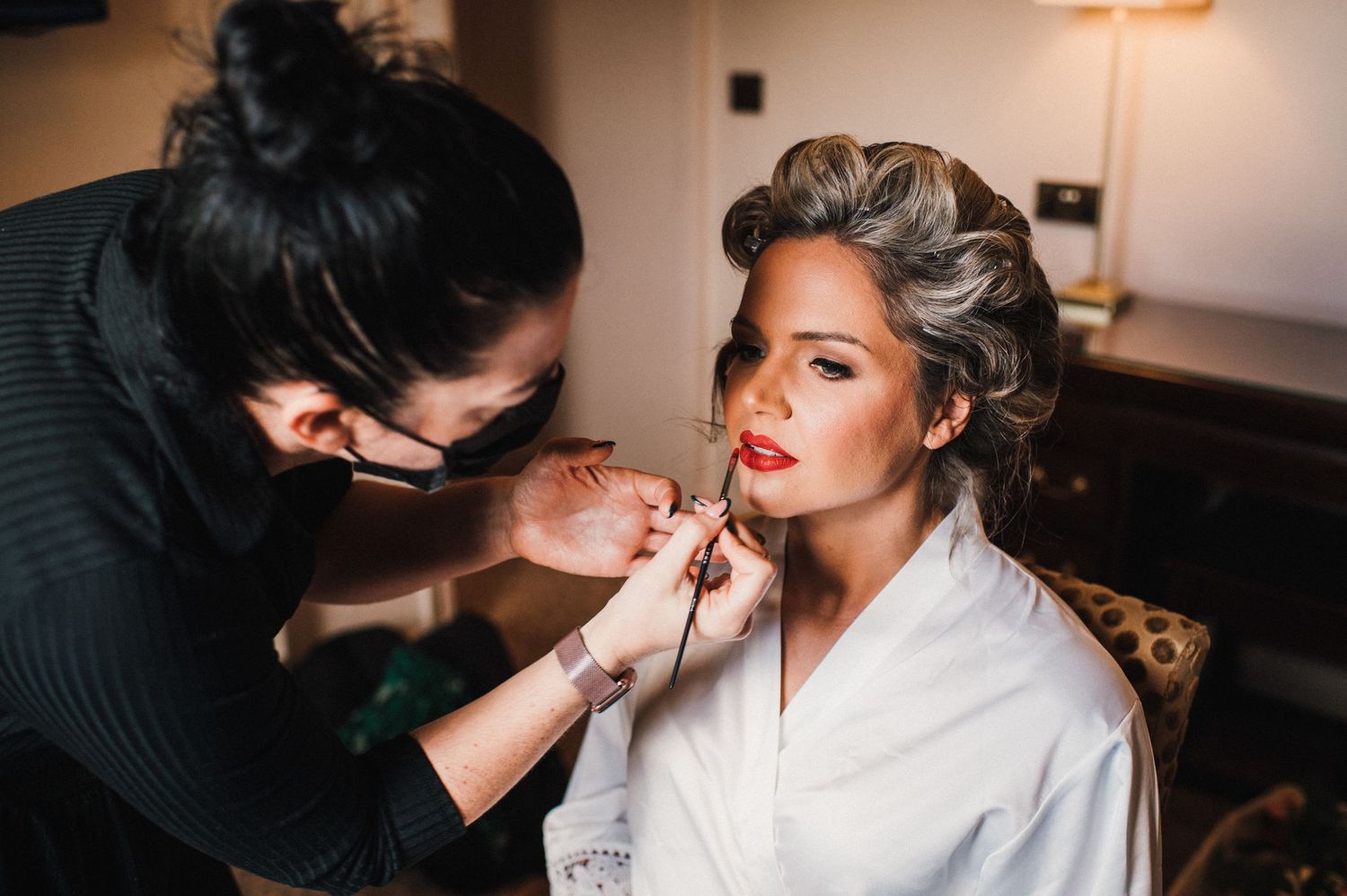 Professional makeup application session in natural window light.