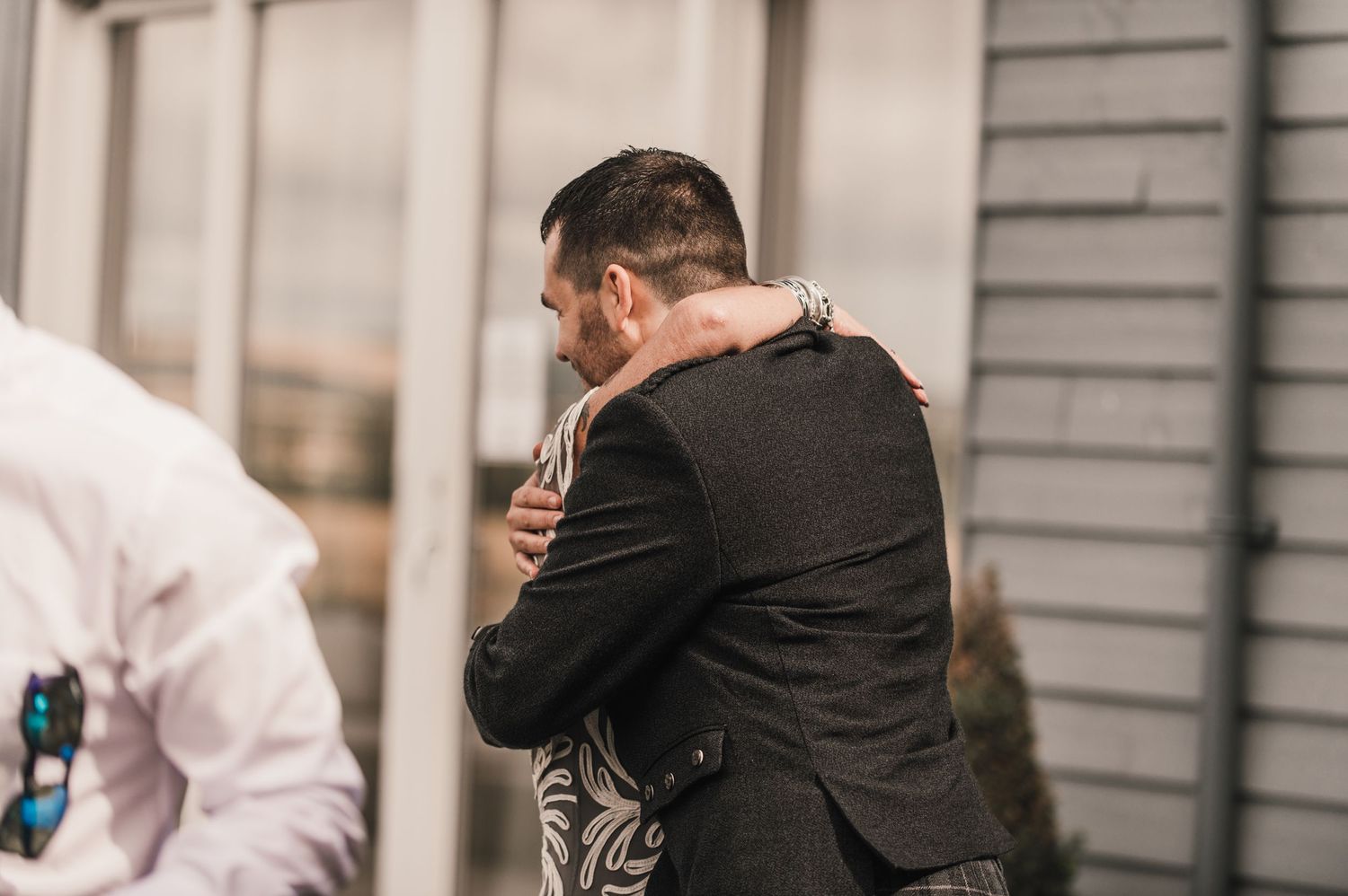 Intimate embrace shared between wedding guests during outdoor celebration.