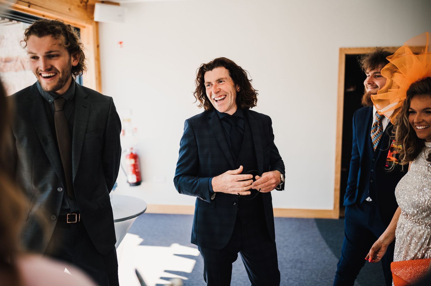 Candid moment of guests laughing and sharing stories at an indoor wedding reception.