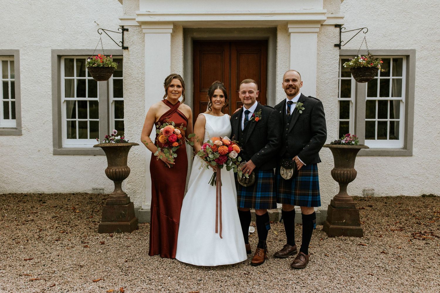 Wedding party posed in front of historic white building with classic architectural details.