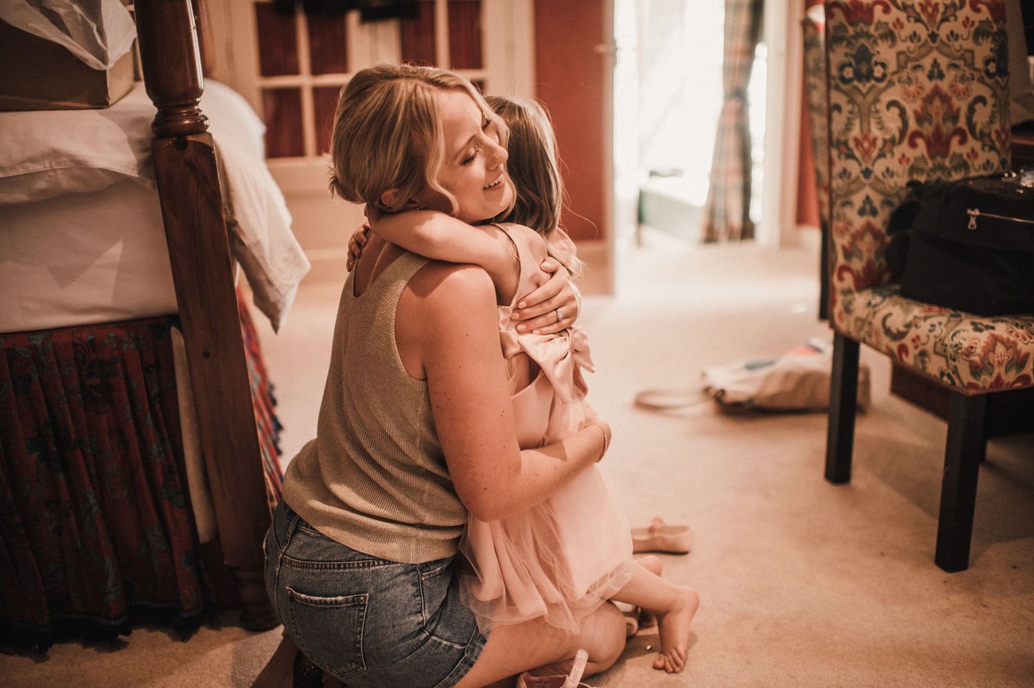 A tender moment of embrace in a warmly lit room with soft carpet and vintage furniture.