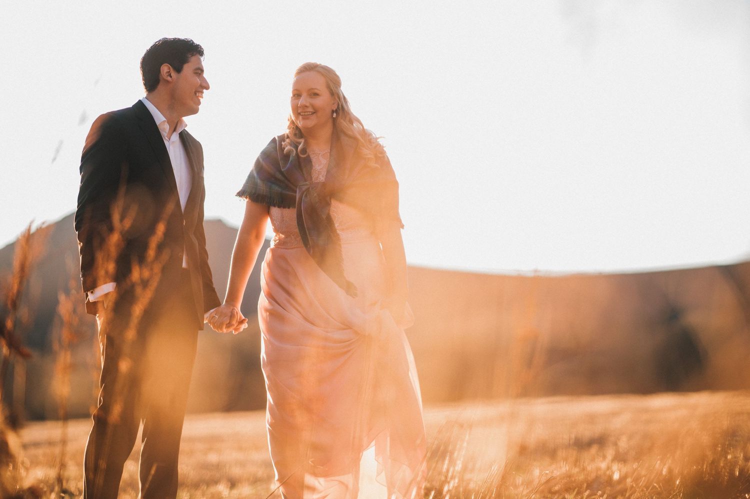 A couple shares an intimate moment in a sunlit meadow during golden hour.