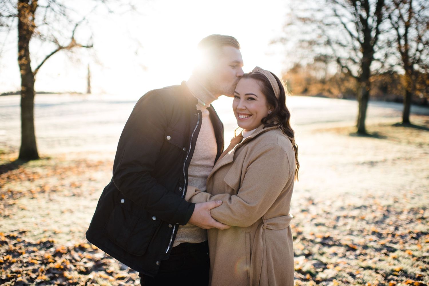Joyful couple laughing together in sunlit autumn park setting.