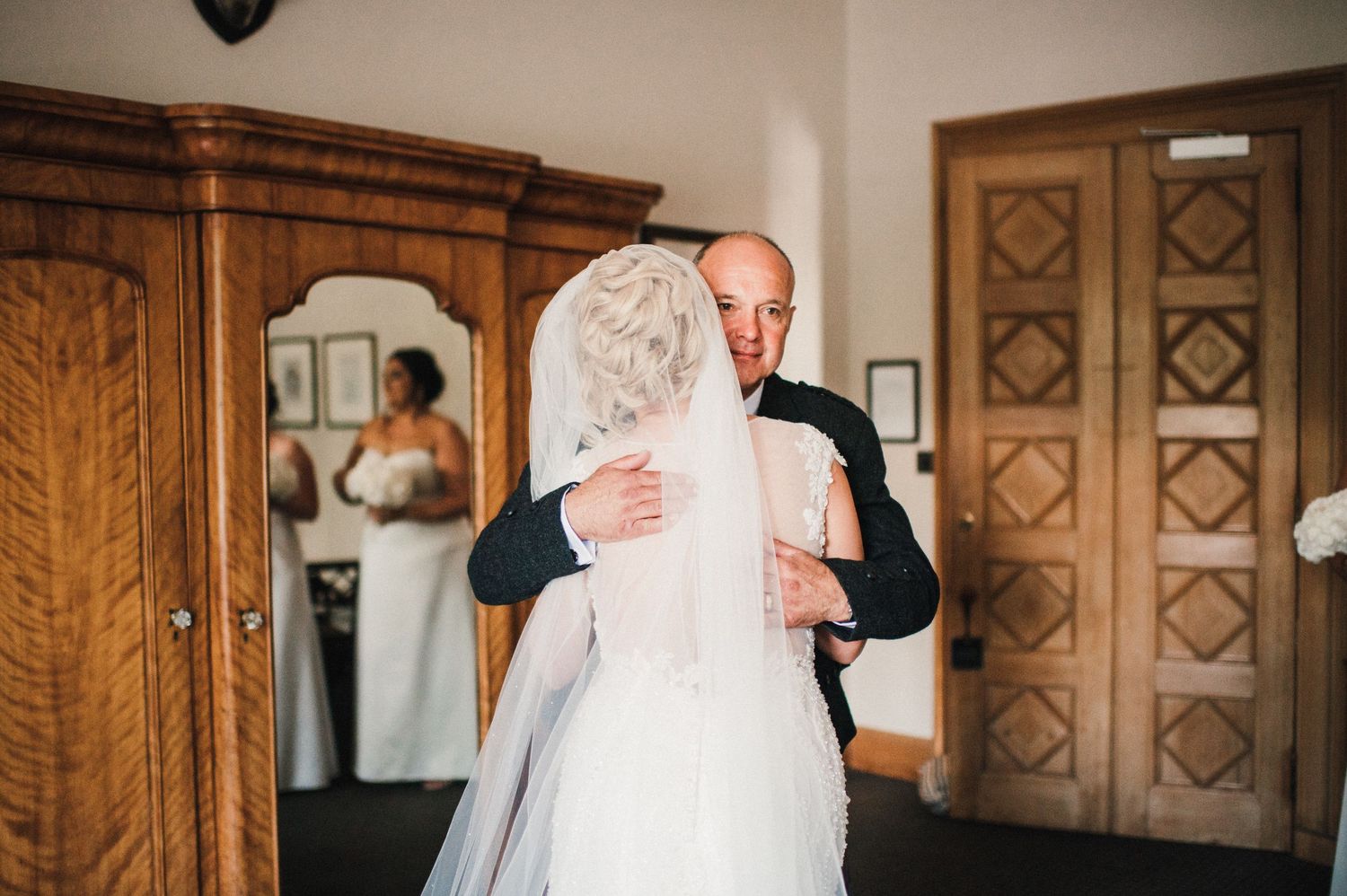 An emotional first look moment captured between two people in a room with wooden furniture.