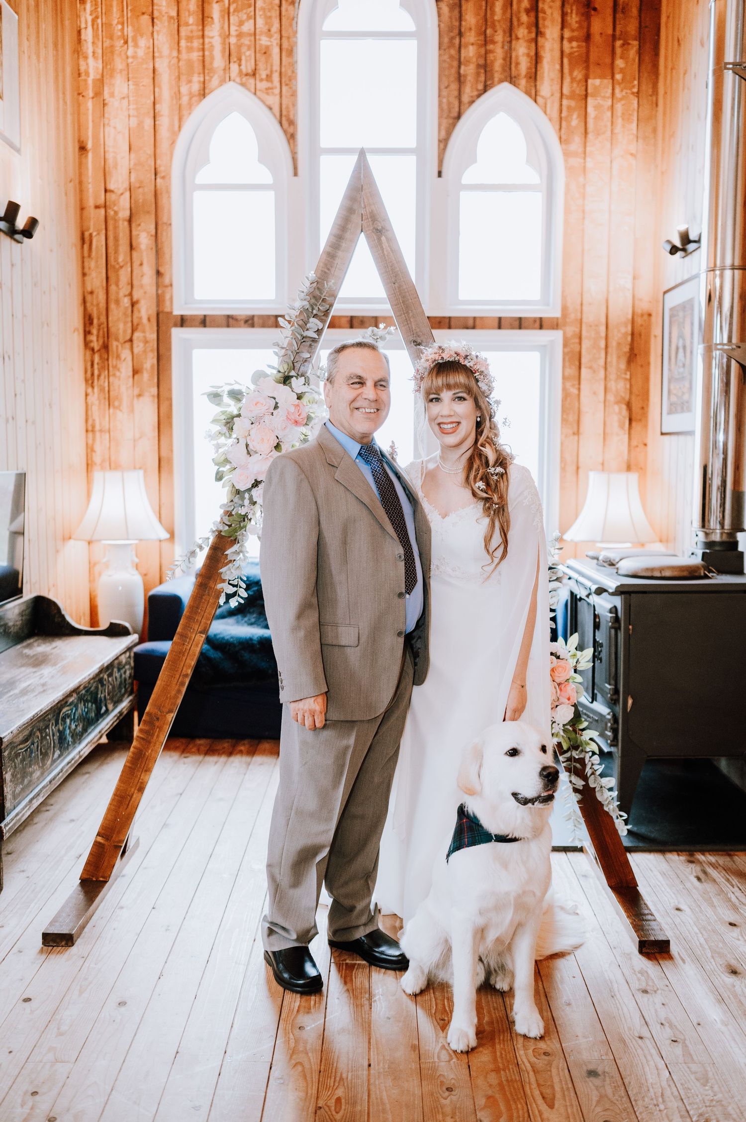 Wedding portrait in rustic chapel with white dog and floral decorated A-frame.