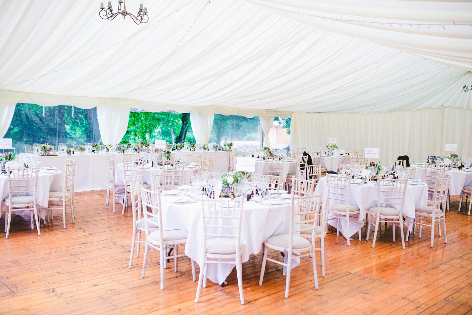 Wedding reception setup with white draped ceiling and elegant table settings.
