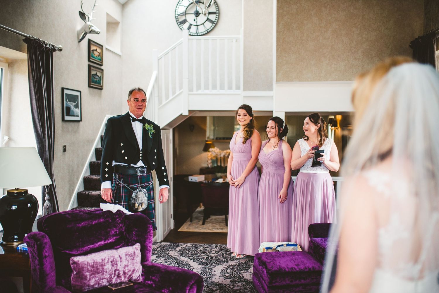 Wedding party getting ready in a room with purple decor and bridesmaids in lavender dresses.