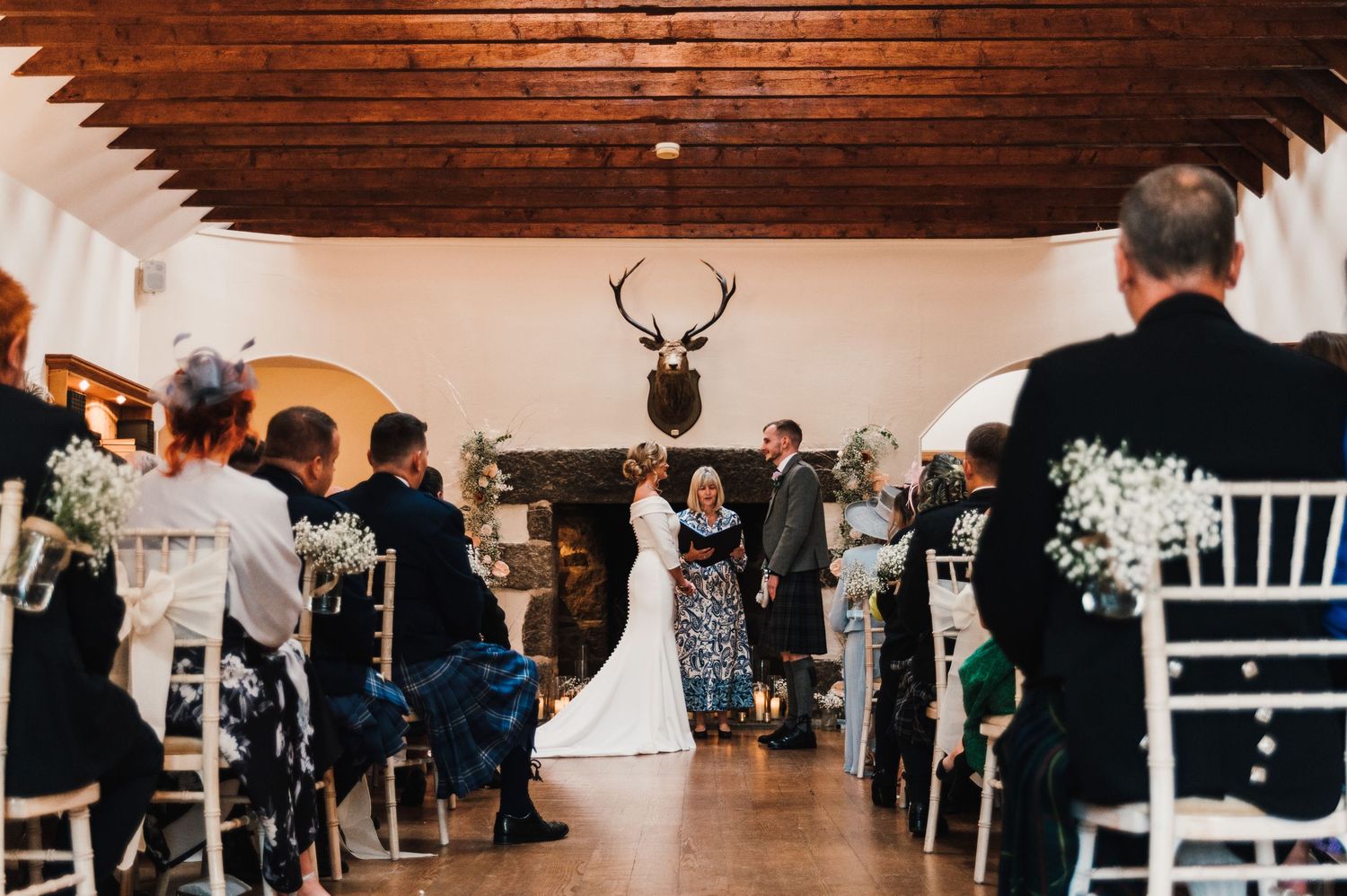 Panoramic view of a rustic wedding reception venue with wooden beams and white chairs.