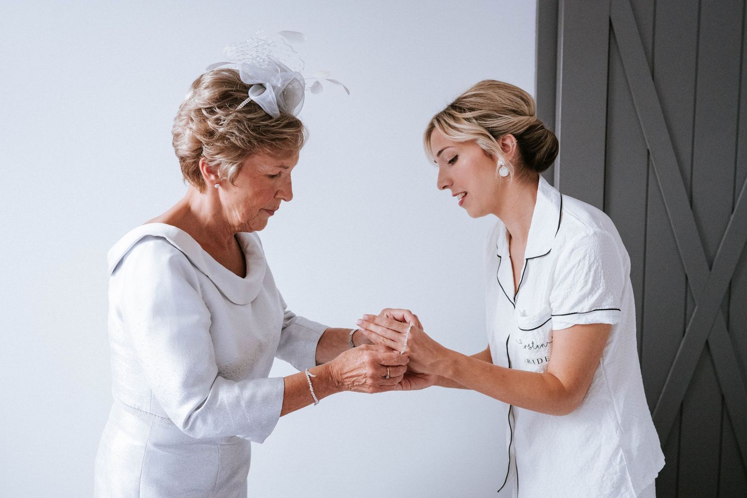 A healthcare worker in white uniform assists an elderly patient with gentle care and support during a medical visit.