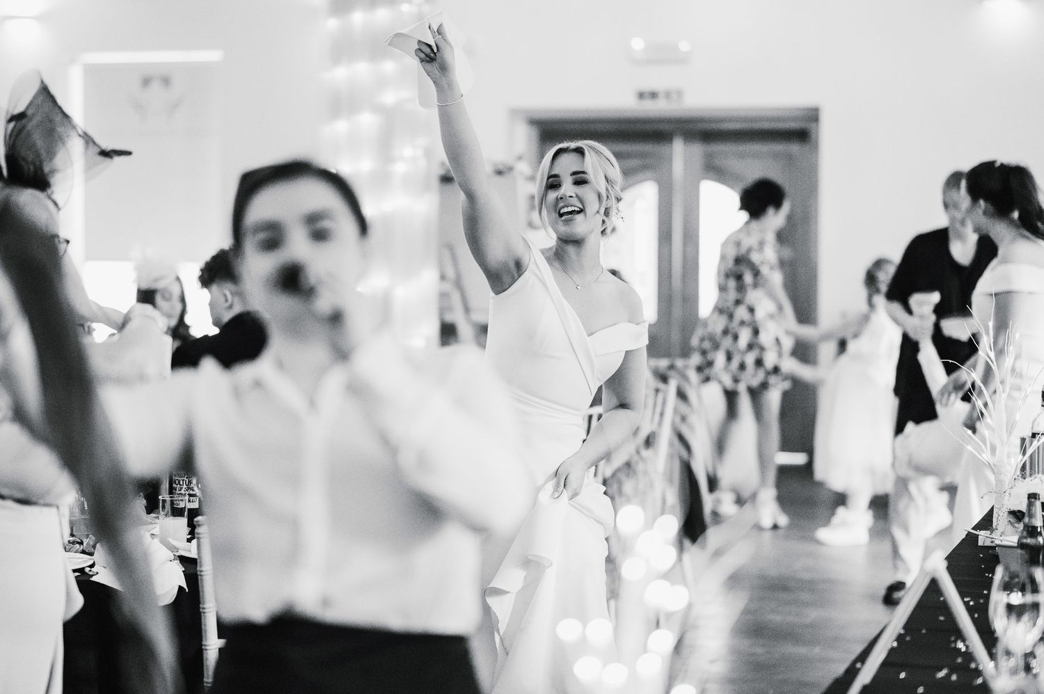 Logie House Wedding Photography. Black and white candid photo of wedding guests celebrating with energetic expressions.