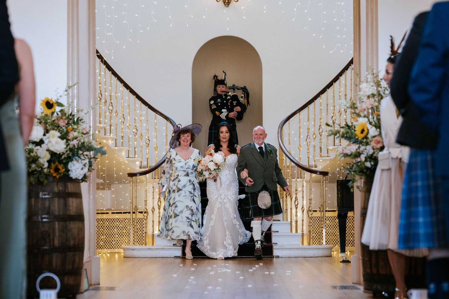 Fasque Castle Wedding Photography. Wedding ceremony in progress in an elegant white chapel with floral arrangements.