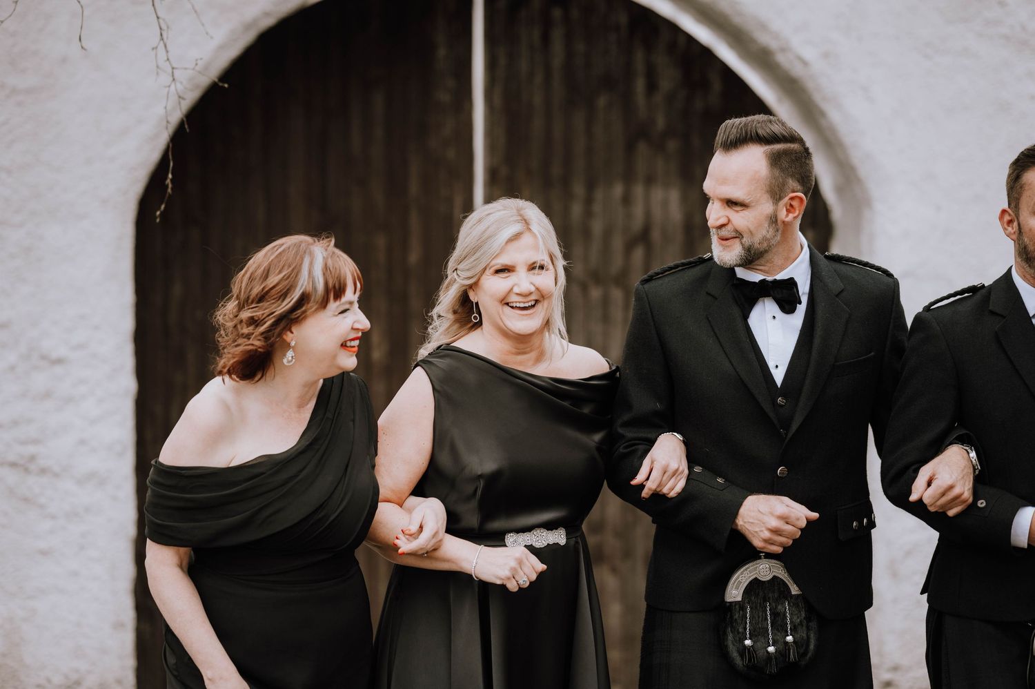 Logie House Wedding Photography. Candid moments of wedding party laughing together in front of stone wall.
